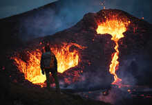 Man Explorer Observing The Magma Sparks Out Of The Volcano Fagradalsfjall In Iceland Between Clouds Of Smoke