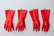 © Ruben Soto/ADDICTIVE STOCK - Composition of red rubber gloves hanging on clothes pins on white background in studio