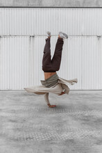 Unrecognizable Male Dancer Showing Breakdance Movement While Balancing On Arms And Performing Hand Hops On Concrete Ground In Urban Area