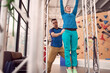 © Sergey Mironov/ADDICTIVE STOCK - From below of female doing pull ups on horizontal bar with help of instructor while training in modern climbing center