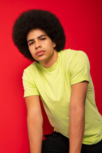 Young Self Confident African American Male In Casual T Shirt Looking At Camera On Red Background