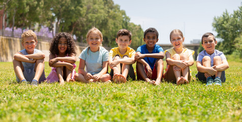 happy children sitting on the green grass on a sunny day