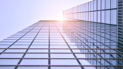 Modern architecture with sun ray. Glass and steel facade on a bright sunny day with sunbeams on the blue sky. Economy, finances, business activity concept.