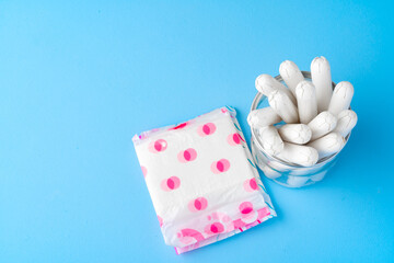 Wall Mural - Female pads and tampons on blue paper background