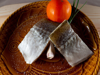 Wall Mural - Closeup shot of slightly salted raw fish fillets with green onion and tomato on a plate