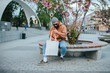 © San4ezz007 - Street style portrait of young hipster man wearing brown blank hoodie with white blank textile eco shopping bag or tote bag. Mock up for design