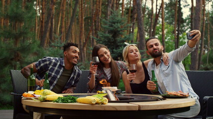 Wall Mural - Smiling friends making selfie outdoors. Happy people doing photo on smartphone