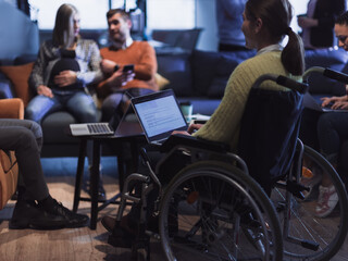 Young woman in wheelchair working on laptop at office. Getting an education at home concept