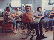© .shock - Disabled businessman in a wheelchair at work in modern open space coworking office with team