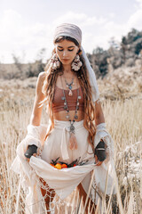 Wall Mural - beautiful stylish young girl holding tangerines in the hem of her skirt on the field