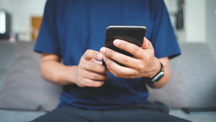 cropped shot man using smart phone while sitting on sofa.