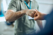 © Drazen - Close-up of auto repairmen greeting with fists at car workshop.