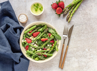 A healthy and delicious salad made from fresh strawberries, green asparagus, feta cheese with vegetable leaves. Vegetarian seasonal food. Detox diet meal.