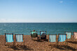 A couple relaxing on the striped chairs in Brighton beach, England         