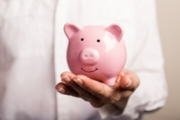 Wall Mural - Piggy bank in hand on light background, space for text. Finance, saving money. Business to success and saving for retirement concept