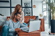 © gstockstudio - Happy young couple using laptop and smiling while spending time at home