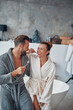© gstockstudio - Happy young couple in bathrobes cleaning teeth while doing morning routine