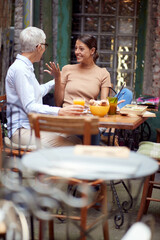 Wall Mural - An older woman and her young female friend are so excited while talking in the bar. Leisure, bar, friendship, outdoor