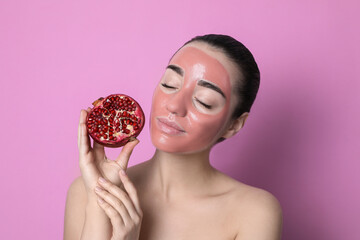 Wall Mural - Woman with pomegranate face mask and fresh fruit on pink background