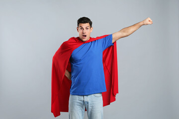 Wall Mural - Man wearing superhero cape on grey background