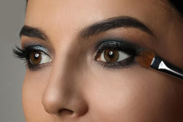 Applying dark eye shadow with brush onto woman's face, closeup. Beautiful evening makeup