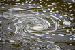Swirl of water foam in shape of a spiral on river surface