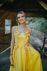 Canvas Print - Gorgeous blonde female in an elegant yellow dress posing next to a wooden shelter