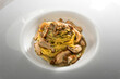 Tajarin with porcini mushrooms or Boletus edulis, fettuccine pasta from Alba, Langhe, Piedmont, Italy, close up in white dish