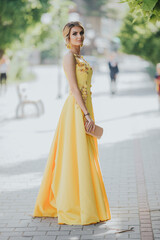 Wall Mural - Vertical portrait of a gorgeous Caucasian blonde female in an elegant yellow dress looking back