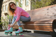 © New Africa - Woman lacing roller skates while sitting on bench outdoors