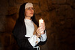 Young nun devoutly with candle