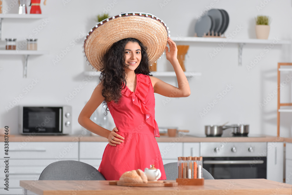 Young woman with sombrero hat in kitchen