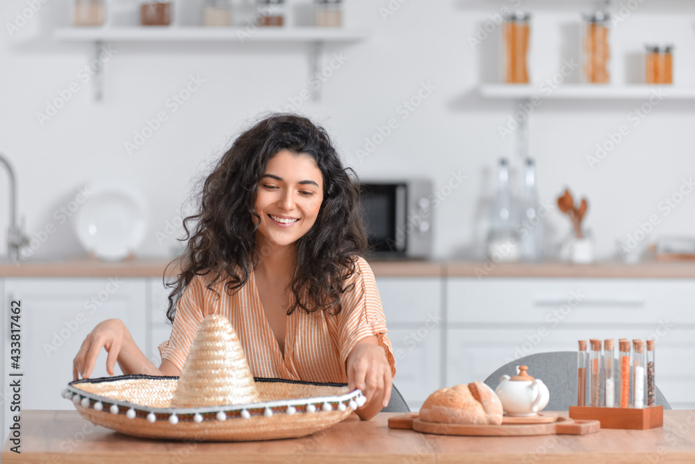 Young woman with sombrero hat in kitchen
