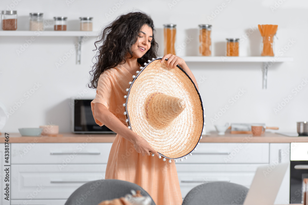 Young woman with sombrero hat in kitchen