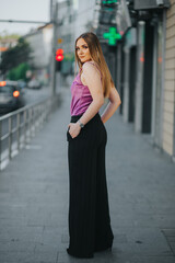 Wall Mural - Gorgeous Caucasian female in stylish purple and black outfit posing in the street