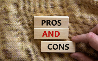 Pros and cons symbol. Wooden blocks with words 'Pros and cons'. Beautiful canvas background, businessman hand. Business, pros and cons concept, copy space.