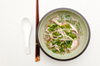 Top view of Vietnamese pho soup with a spoon and Chinese wooden sticks isolated on a white surface