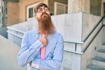 Sticker - Young redhead businessman with serious expression and crossed arms standing at the city.