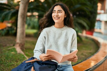 Young middle east student girl smiling happy reading book at the city