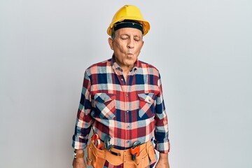 Poster - Senior hispanic man wearing handyman uniform making fish face with lips, crazy and comical gesture. funny expression.