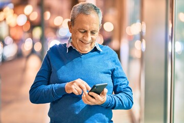 Wall Mural - senior grey-haired man smiling happy using smartphone at the city.