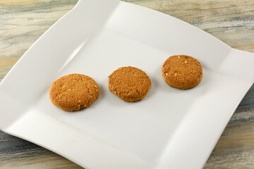 Wall Mural - Three Turkish roasted hazelnut cookies in a row on white snack plate