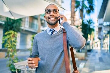 Canvas Print - Young african american businessman talking on the smartphone and drinking take away coffee at the city.