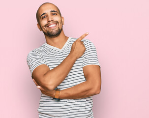 Sticker - Hispanic adult man wearing casual clothes with a big smile on face, pointing with hand and finger to the side looking at the camera.