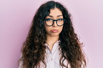 Young brunette woman with curly hair wearing casual clothes and glasses depressed and worry for distress, crying angry and afraid. sad expression.