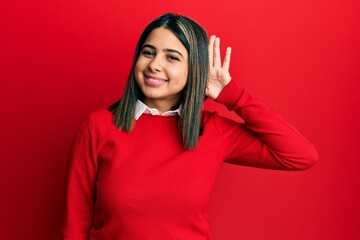 Poster - Young latin woman wearing casual clothes smiling with hand over ear listening an hearing to rumor or gossip. deafness concept.