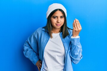 Poster - Young latin woman wearing cute wool cap doing italian gesture with hand and fingers confident expression