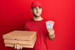 © Krakenimages.com - Young caucasian man holding delivery box and swiss franc banknotes smiling looking to the side and staring away thinking.