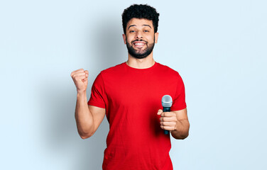 Poster - Young arab man with beard singing song using microphone screaming proud, celebrating victory and success very excited with raised arm