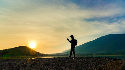 Poster - Silhouette of a photographer taking a photo at sunset beside the mountain